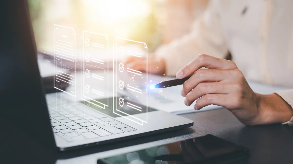 Osoba wypełniająca cyfrowe formularze na laptopie za pomocą pióra elektronicznego